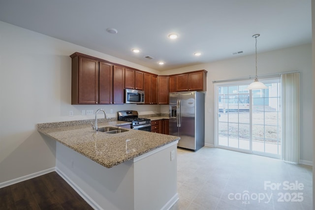 kitchen featuring sink, light stone counters, hanging light fixtures, kitchen peninsula, and stainless steel appliances