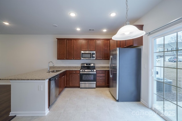 kitchen featuring sink, kitchen peninsula, pendant lighting, stainless steel appliances, and light stone countertops