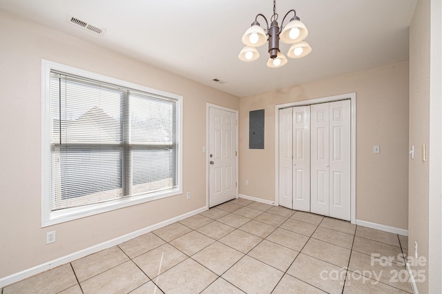 unfurnished bedroom with light tile patterned floors, electric panel, an inviting chandelier, and a closet