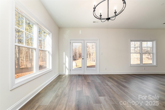 unfurnished dining area featuring hardwood / wood-style flooring, plenty of natural light, and a chandelier