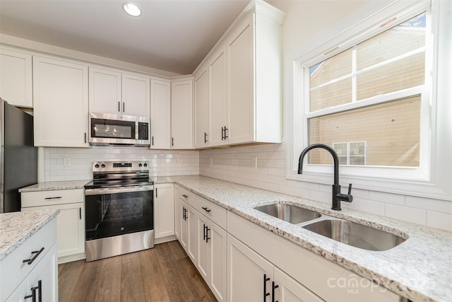 kitchen with sink, light stone countertops, white cabinets, and appliances with stainless steel finishes