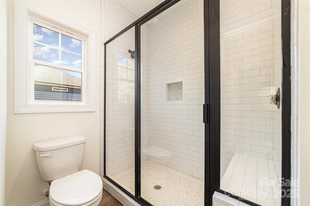 bathroom featuring a shower with door and toilet