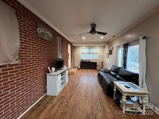 living room with crown molding, brick wall, a wealth of natural light, and hardwood / wood-style floors