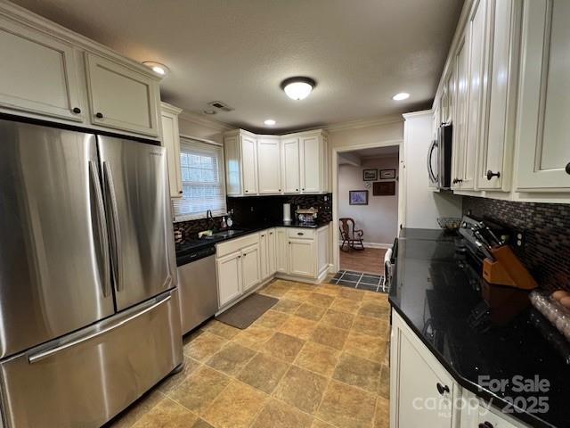 kitchen featuring decorative backsplash, stainless steel appliances, and white cabinets