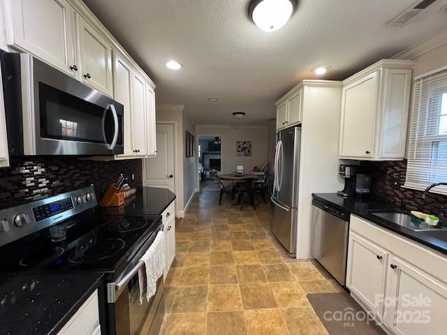 kitchen featuring stainless steel appliances, white cabinetry, sink, and tasteful backsplash