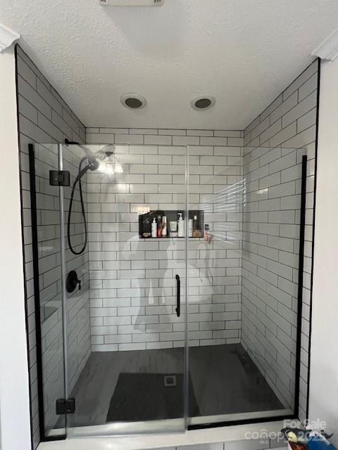 bathroom with a shower with door and a textured ceiling