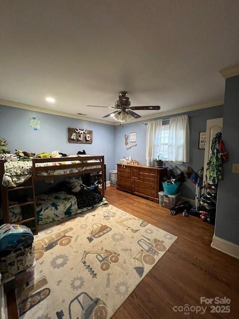 bedroom with hardwood / wood-style floors, ornamental molding, and ceiling fan