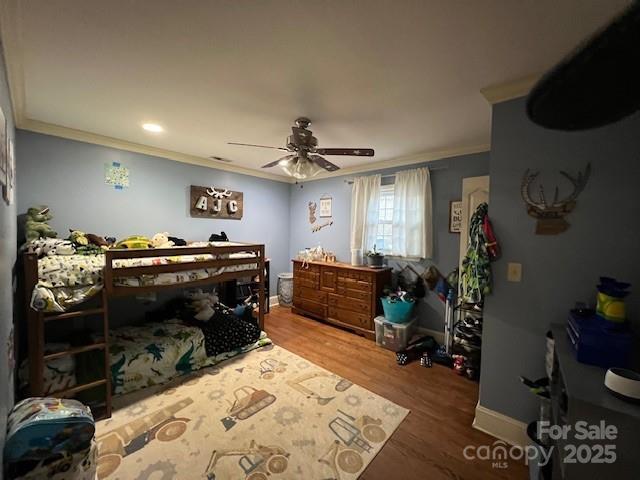 bedroom with hardwood / wood-style flooring, ornamental molding, and ceiling fan