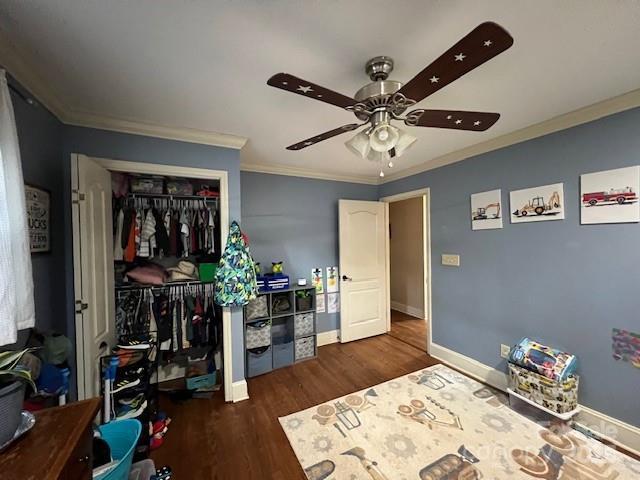 bedroom with crown molding, dark wood-type flooring, a closet, and ceiling fan