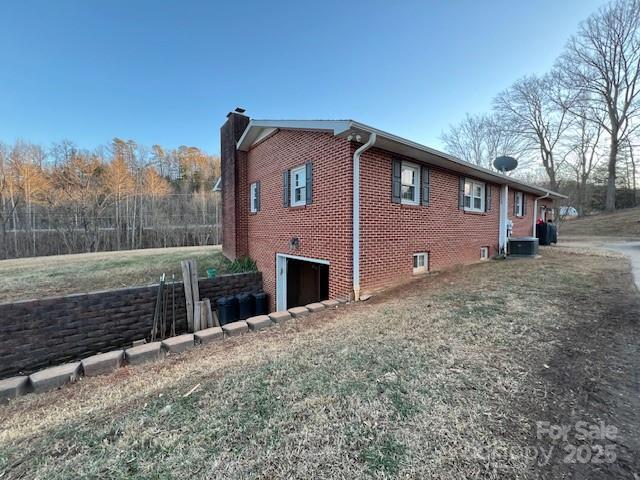 view of side of home featuring a garage, a lawn, and central air condition unit