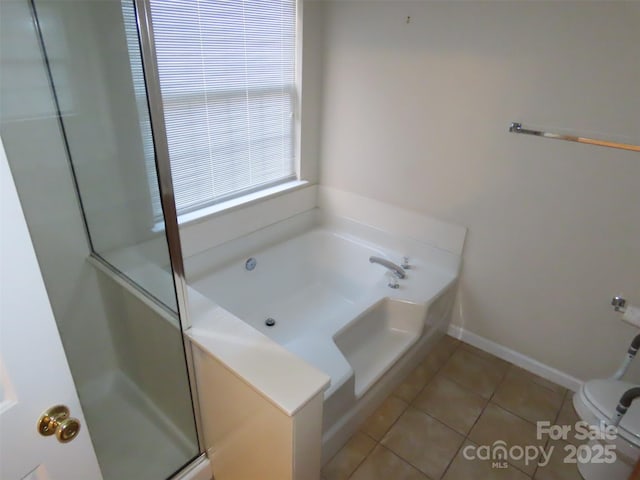 bathroom featuring tile patterned flooring, a tub, and toilet