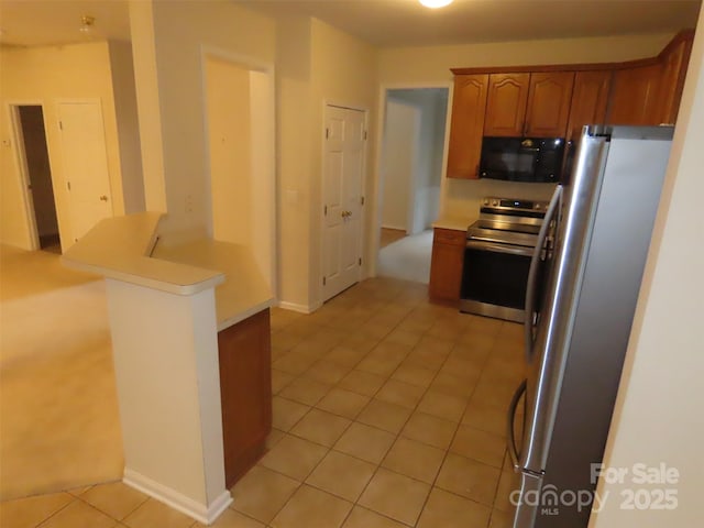 kitchen with light tile patterned floors, kitchen peninsula, and appliances with stainless steel finishes