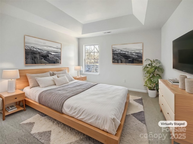 bedroom with light colored carpet and a raised ceiling