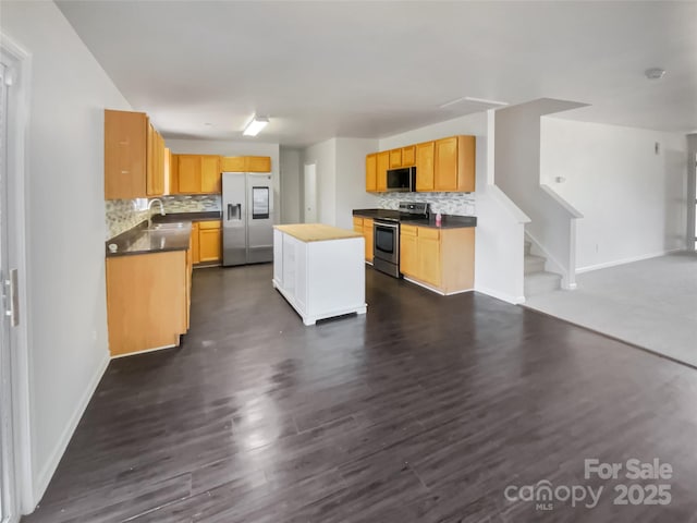 kitchen with appliances with stainless steel finishes, dark hardwood / wood-style floors, a kitchen island, and backsplash