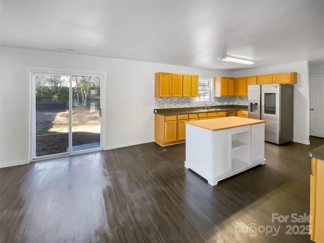 kitchen featuring sink, dark wood-type flooring, stainless steel refrigerator with ice dispenser, a kitchen island, and decorative backsplash