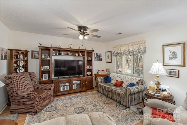 living room featuring a textured ceiling, ceiling fan, and light hardwood / wood-style flooring