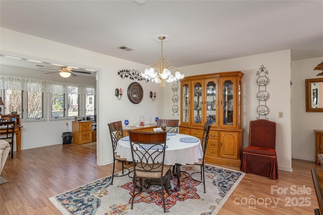 dining area featuring hardwood / wood-style flooring and ceiling fan with notable chandelier