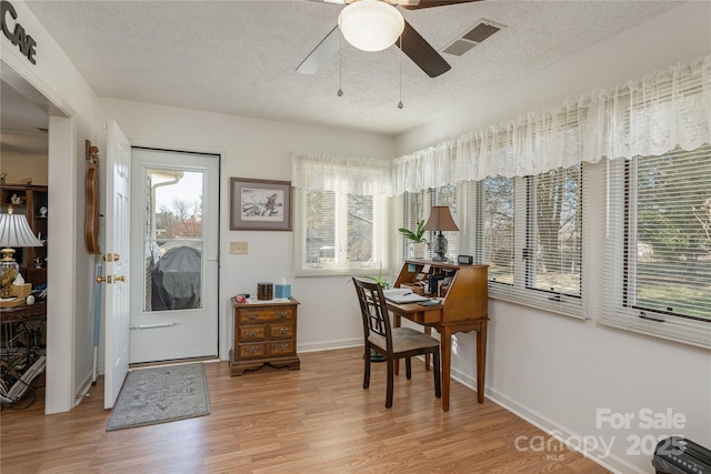 home office featuring ceiling fan, a healthy amount of sunlight, a textured ceiling, and light hardwood / wood-style flooring