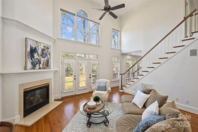 living room featuring crown molding, ceiling fan, a high end fireplace, and hardwood / wood-style floors