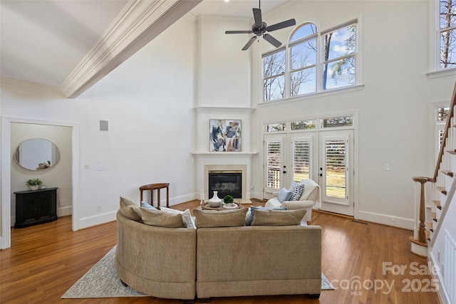 living room featuring french doors, wood-type flooring, ornamental molding, a towering ceiling, and ceiling fan