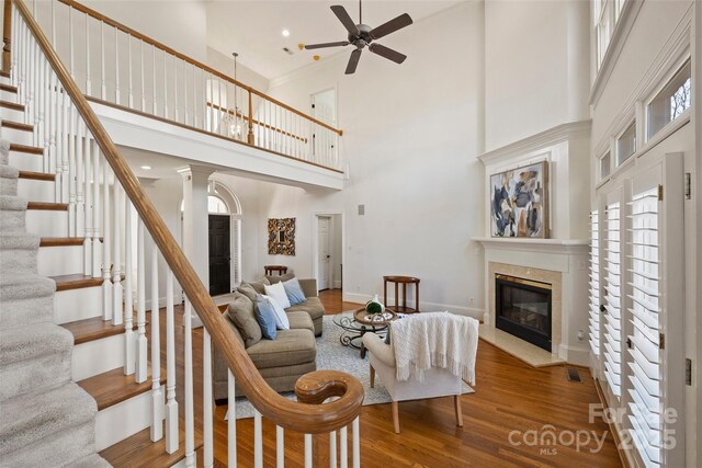 living room with ceiling fan, wood-type flooring, and a towering ceiling