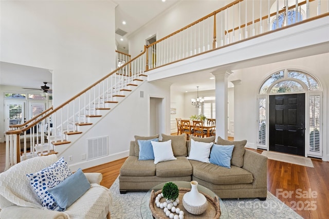 living room featuring ornamental molding, wood-type flooring, decorative columns, and a high ceiling