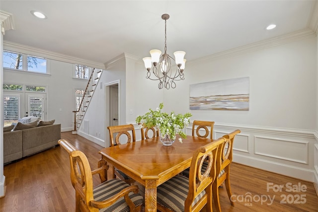 dining room with hardwood / wood-style floors, crown molding, and a chandelier