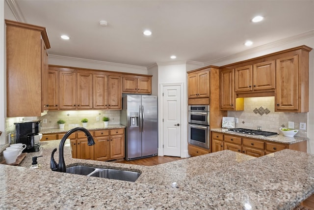 kitchen with light stone counters, stainless steel appliances, kitchen peninsula, and sink