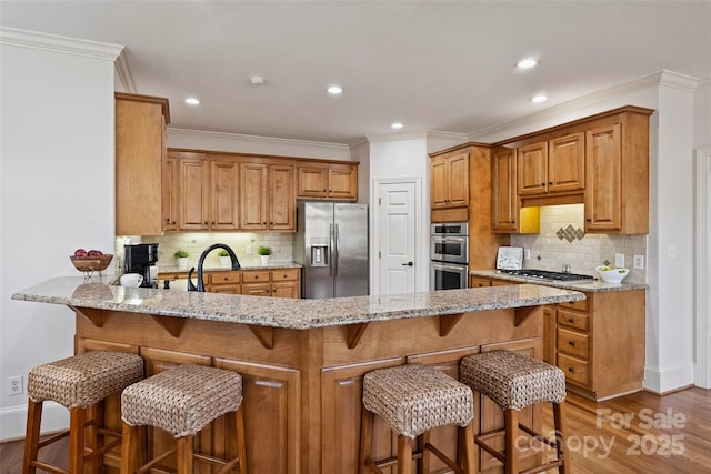 kitchen with appliances with stainless steel finishes, a breakfast bar area, light stone counters, and kitchen peninsula