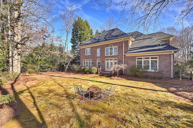 back of property featuring a yard and an outdoor fire pit