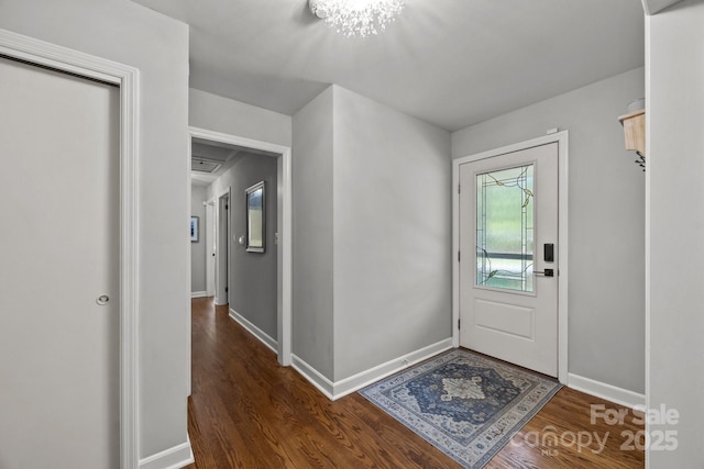 foyer featuring an inviting chandelier, baseboards, and dark wood-style flooring