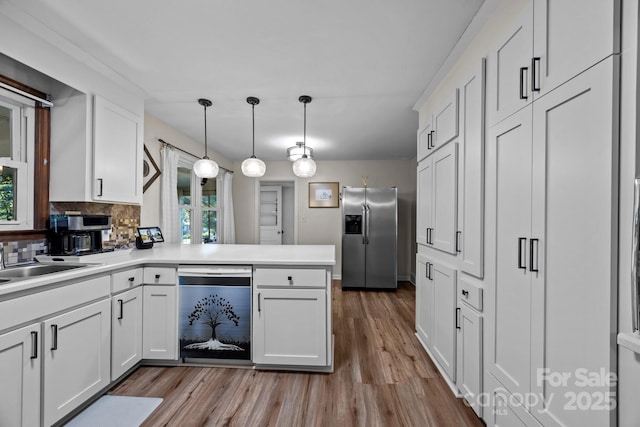 kitchen featuring dishwashing machine, hanging light fixtures, stainless steel refrigerator with ice dispenser, white cabinets, and kitchen peninsula