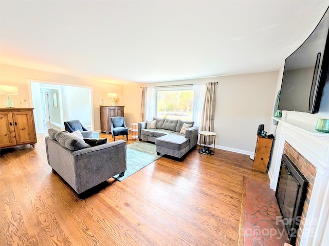 living room with baseboards, a fireplace with flush hearth, and wood finished floors