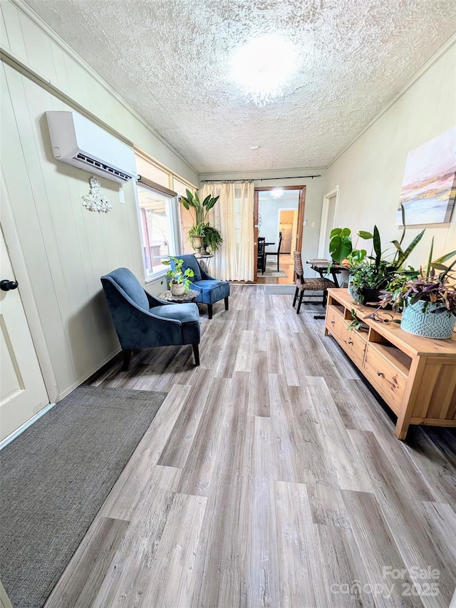 corridor featuring a wall mounted air conditioner, light hardwood / wood-style flooring, and a textured ceiling