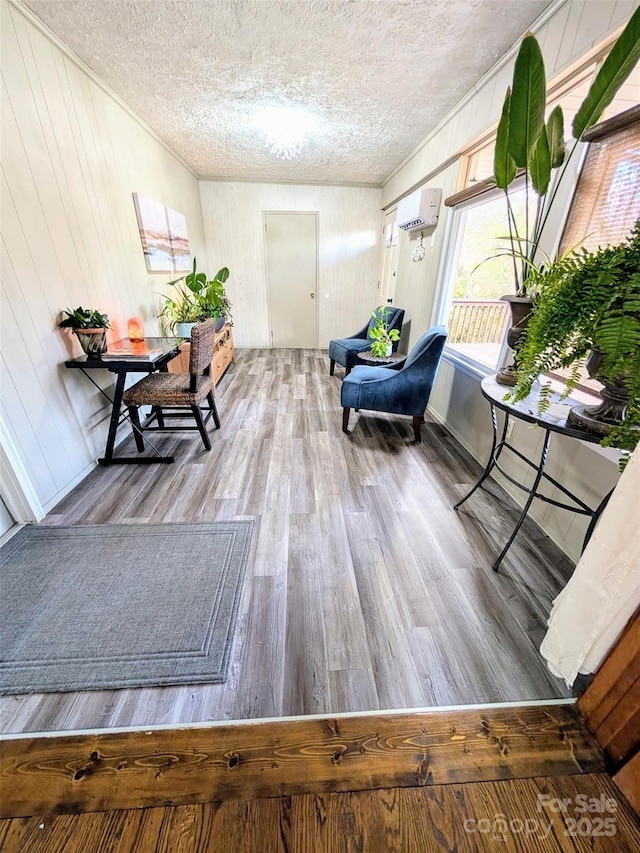 living area featuring a textured ceiling, wood-type flooring, and a wall mounted AC