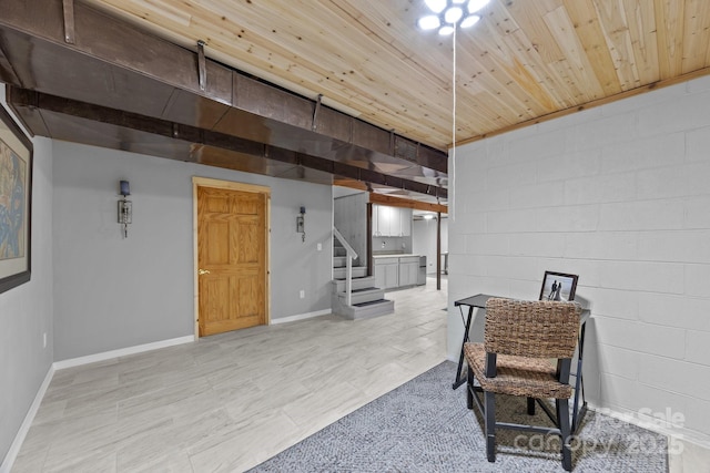 living area with wooden ceiling, stairway, concrete block wall, and baseboards