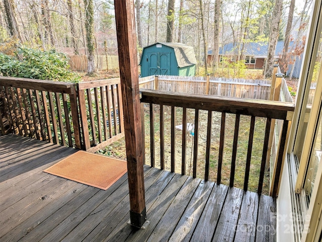 deck with an outbuilding, a storage shed, and fence