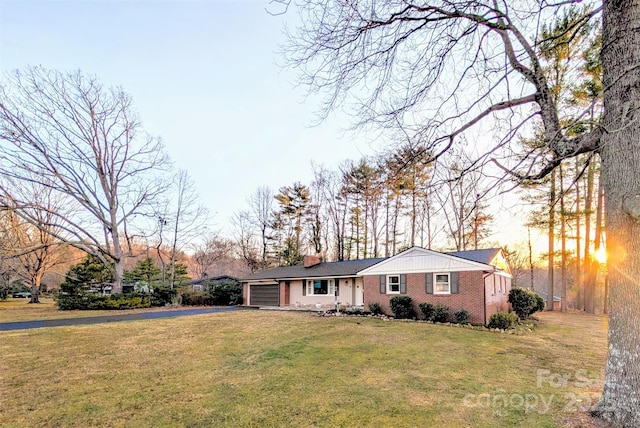 single story home featuring aphalt driveway, a front lawn, and an attached garage