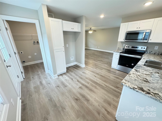 kitchen with light hardwood / wood-style flooring, ceiling fan, white cabinetry, stainless steel appliances, and light stone counters