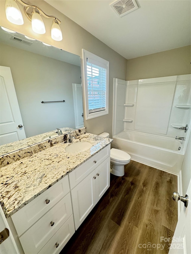 full bathroom with  shower combination, toilet, hardwood / wood-style floors, and vanity