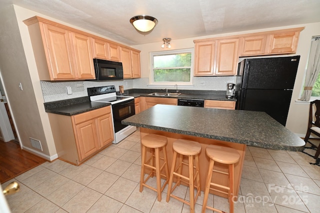 kitchen featuring a kitchen island, sink, a breakfast bar area, and black appliances