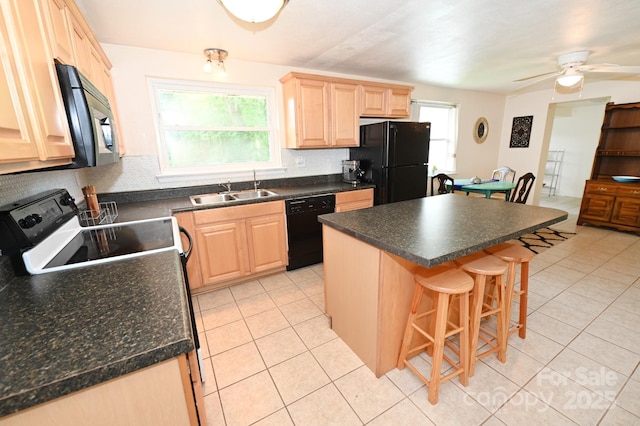 kitchen with light brown cabinetry, sink, a kitchen island, and black appliances