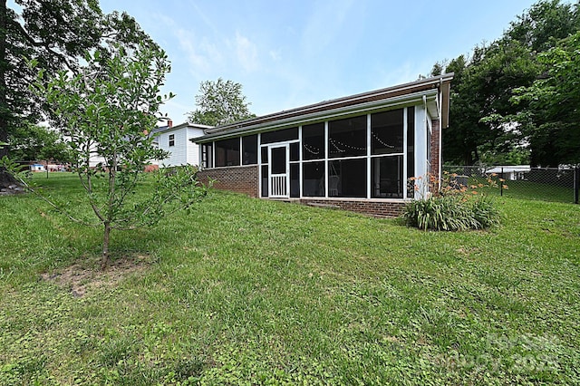 back of house with a lawn and a sunroom