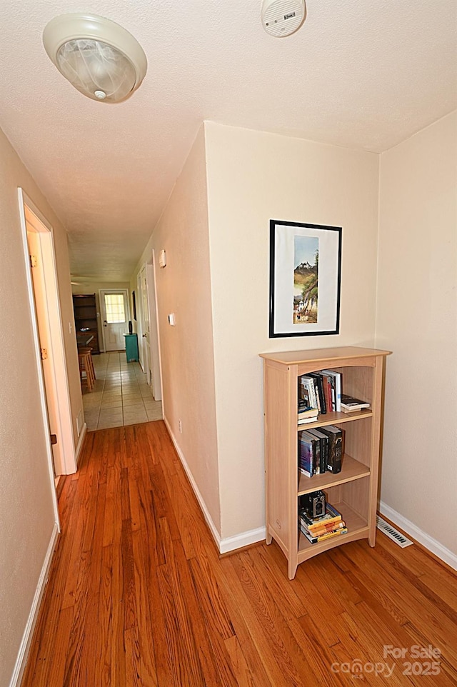 hallway featuring wood-type flooring and a textured ceiling