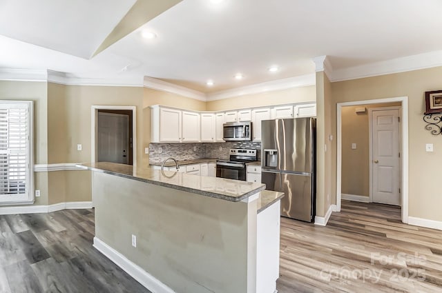 kitchen featuring stone counters, white cabinetry, stainless steel appliances, tasteful backsplash, and kitchen peninsula