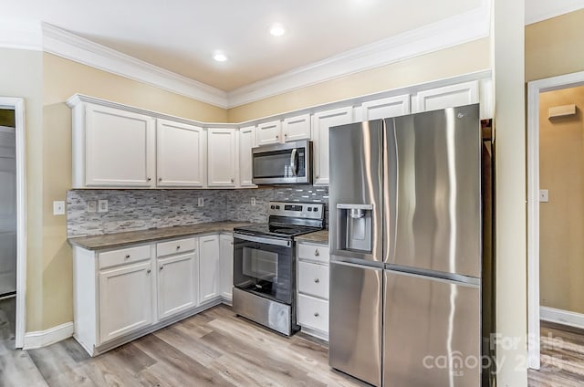 kitchen with backsplash, white cabinets, and appliances with stainless steel finishes