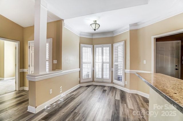 unfurnished dining area featuring an inviting chandelier, ornamental molding, dark hardwood / wood-style floors, and decorative columns