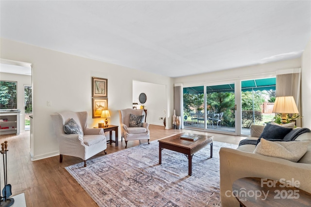 living room featuring wood-type flooring, a healthy amount of sunlight, and baseboards