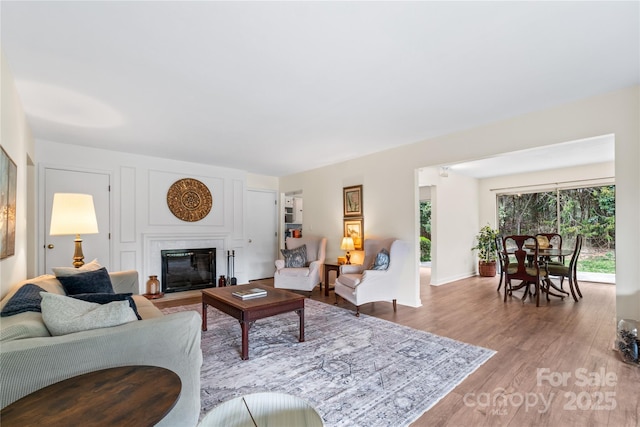 living area with a fireplace with flush hearth and wood finished floors