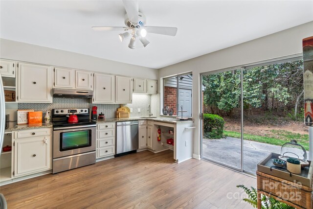 kitchen with light wood finished floors, backsplash, appliances with stainless steel finishes, white cabinetry, and under cabinet range hood